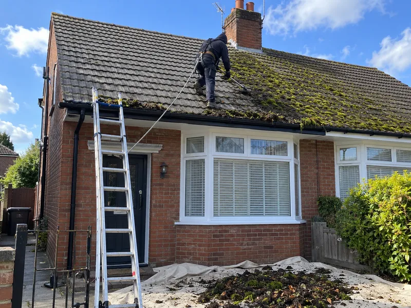 Roof and gutters being cleaned of moss on a house in Manchester